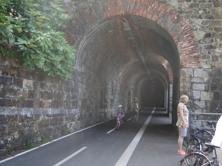 Ciclisti in una galleria della pista Levanto–Framura