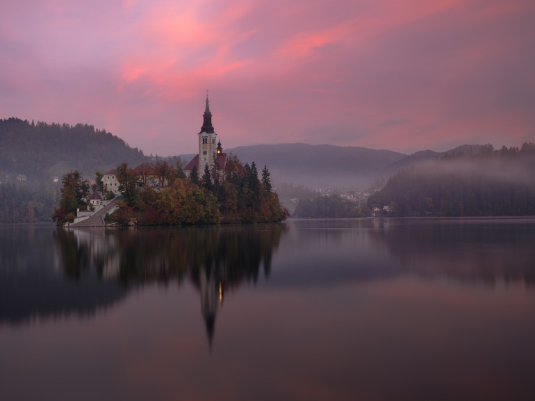 the island in the lake with the church at the sun set