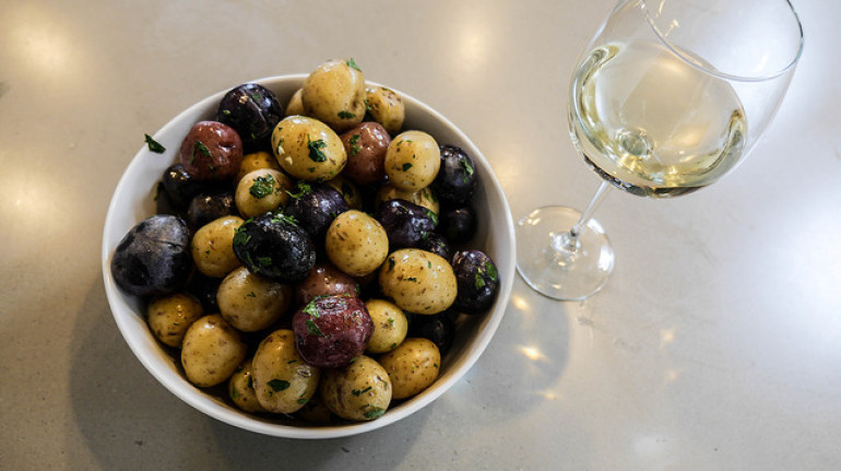 un bicchiere di vino accanto a una ciotola di olive